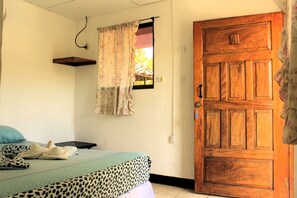 Ein Schlafzimmer mit einem Bett, einer Holztür, einem Fenster mit Vorhang und einem an der Wand befestigten Regal.