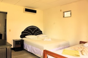 A bedroom with a bed, a nightstand, a dresser, an air conditioning unit, and a window.