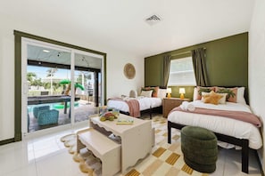 A hotel room with a bed, a desk, a chair, a bench, a window, and a view of the outside. - Mins to Beach • Backyard Oasis • Heated Pool & Spa (West Palm Beach)