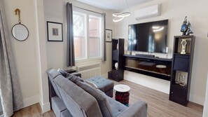Un salon comprenant un canapé, un téléviseur, une cheminée et un radiateur.