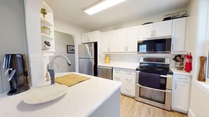 A modern kitchen with white cabinets, stainless steel appliances, a wooden countertop, and a built-in oven. - Your Home Away From Home. 3 Bedrooms and an office, walking distance to Gaslight (Cambridge)
