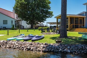 Una propiedad frente al lago con kayaks, un muelle y una zona de estar cubierta.