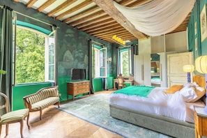 Quarto com uma cama grande, escrivaninha, cadeira e televisão.