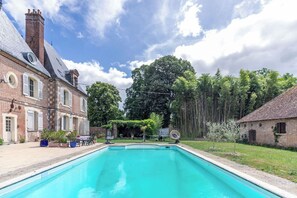 Uma piscina com uma casa de tijolos ao fundo.