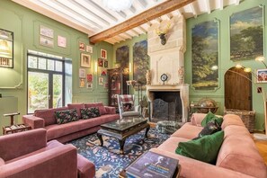 A cozy living room with a fireplace, green walls, and various framed pictures.