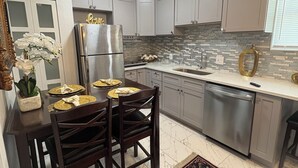 A kitchen with white cabinets, a stainless steel refrigerator, a dishwasher, and a dining table set for four. - and welcoming.
Carrollwood Paradise
 2BR Apartment Central Tampa Near Everything (Tampa)