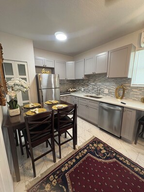 A kitchen with white cabinets, a stainless steel refrigerator, a dishwasher, and a dining table set for four. - and welcoming.
Carrollwood Paradise
 2BR Apartment Central Tampa Near Everything (Tampa)
