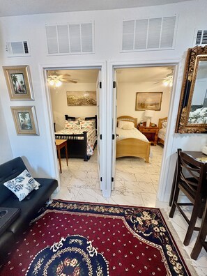Una habitación con cama, una silla, una mesa, un sofá y un espejo grande.