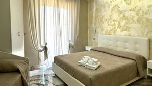 A bedroom with a bed, a nightstand, a wardrobe, and a window with curtains.