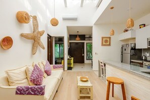 Ein modernes Wohnzimmer mit Sofa, Essbereich, Küche und einer Treppe zu einem weiteren Raum.