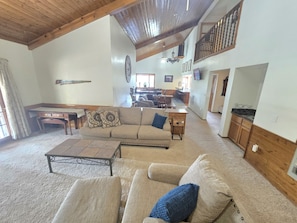 A spacious living room with a high ceiling, a dining area, and a kitchen in the background. - Munds Park Basecamp Cabin (Sedona)