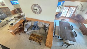 A spacious living area with a large clock, a dining table, and a cozy seating arrangement. - Munds Park Basecamp Cabin (Sedona)