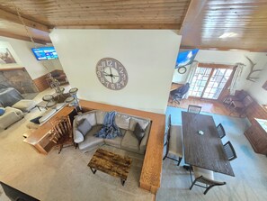 A spacious living area with a large clock, a dining table, and a cozy seating arrangement. - Munds Park Basecamp Cabin (Sedona)