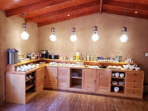 A kitchen with wooden cabinets, a countertop, and hanging light fixtures. - HOSTAL ILLAUCA DE ATACAMA  (San Pedro de Atacama)