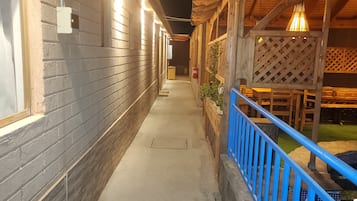 A corridor with a concrete floor, brick walls, and wooden railings.