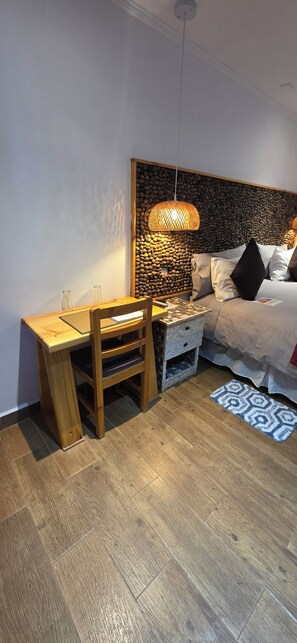 A bedroom with a wooden desk, a bed with a headboard, and a patterned rug. - HOSTAL ILLAUCA DE ATACAMA  (San Pedro de Atacama)