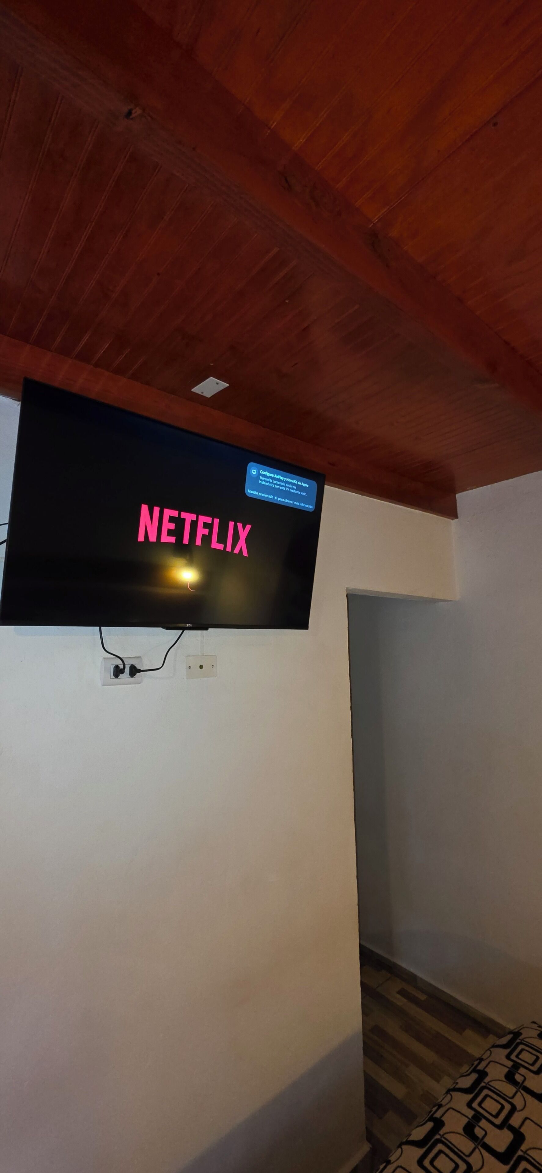 A television mounted on a wall with the word 'NETFLIX' displayed in pink letters.