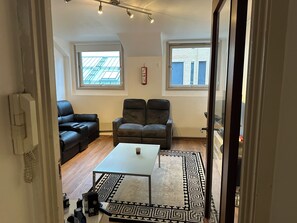 Ein Wohnzimmer mit einer Couch, zwei Sesseln, einem Couchtisch und einem gemusterten Teppich.