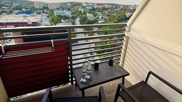 A balcony with a table and chairs, a view of a cityscape, and a railing. - Cozy 2-bedroom apartment in tranquil Iași with AC (Iași)