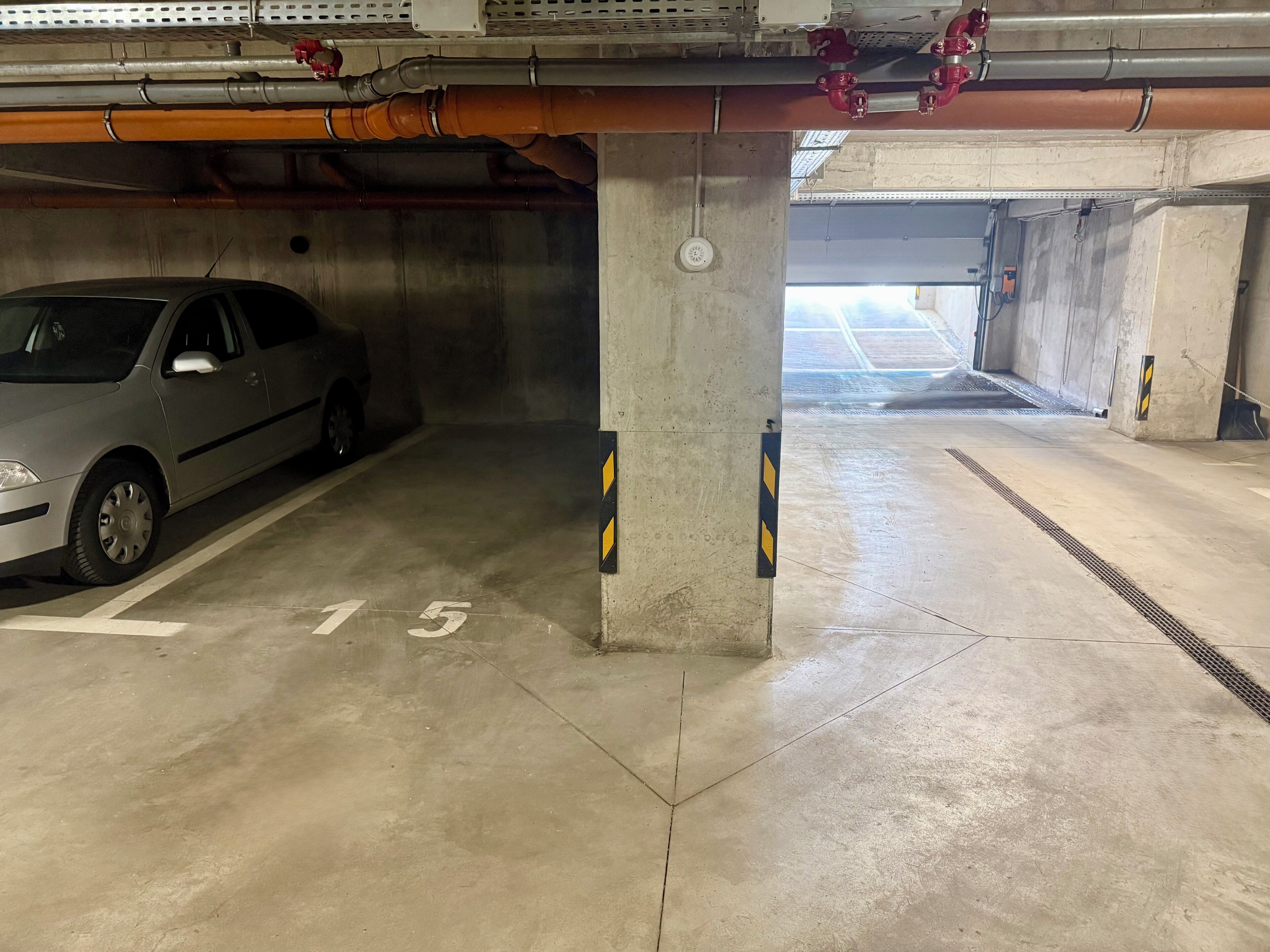 Un parcheggio sotterraneo con un'auto parcheggiata in uno stallo contrassegnato dal numero 15.