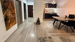 A modern kitchen with dark cabinets, a dining table with chairs, and a statue in the hallway. - Cozy 2-bedroom apartment in tranquil Iași with AC (Iași)