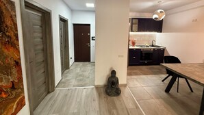 A modern kitchen with dark cabinets, a dining table, and a statue. - Cozy 2-bedroom apartment in tranquil Iași with AC (Iași)