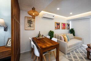 Uma sala de estar moderna com uma mesa de jantar de madeira, um sofá e um lustre.