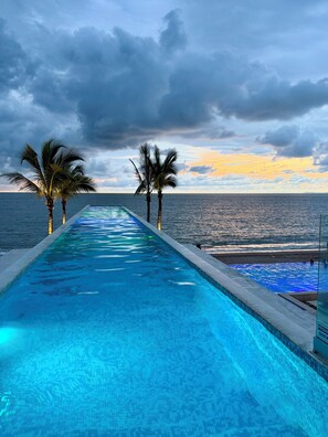 Piscina com vista para o oceano e palmeiras.