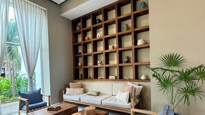 Ein modernes Wohnzimmer mit einer Couch, zwei Couchtischen, einem Sessel, einem Bücherregal und einer Topfpflanze.
