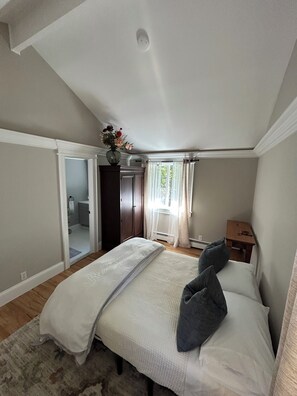 Un dormitorio con una cama, mesita de noche, cómoda y ventana con cortinas.