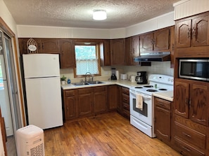 A kitchen with wooden cabinets, a white refrigerator, a stove, and a microwave. - Welcome to Excelsior Springs (Excelsior Springs)