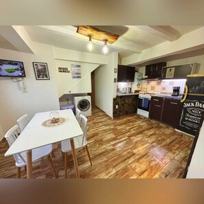 Una cocina compacta con lavadora, un comedor con mesa y sillas, y una encimera con refrigerador y un cartel de Jack Daniel's.