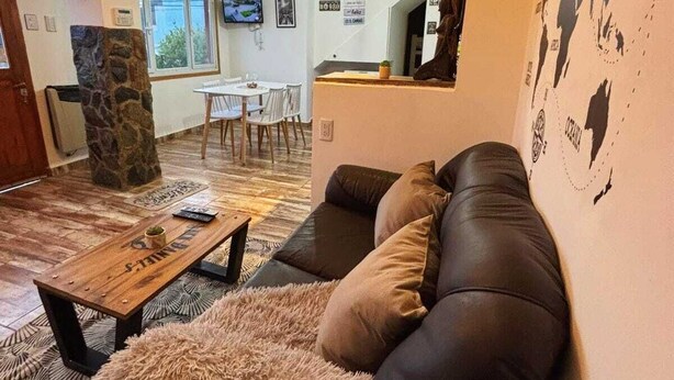 A living room with a leather sofa, a wooden coffee table, and a stone pillar.