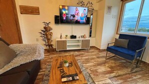 A living room with a TV, sofa, coffee table, and a window.