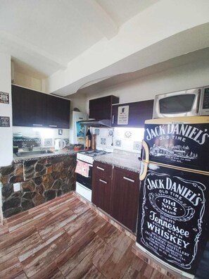 Una cocina con protector contra salpicaduras de piedra, armarios de madera oscura, una estufa y un refrigerador con etiqueta Jack Daniel's.
