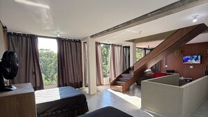 A hotel room with a bed, a desk, a fan, a TV, and a staircase leading to a balcony. - House with infinity pool in Serra de Cantareira (Caieiras)