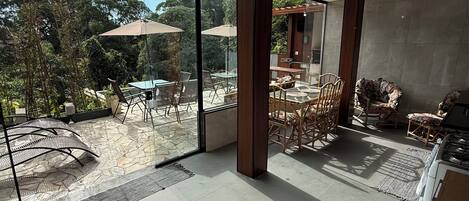 Une pièce spacieuse avec de grandes fenêtres, un coin repas avec des chaises et des tables, et un coin cuisine équipé d’une cuisinière.