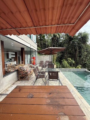 Eine Terrasse mit Pool, Gartenmöbeln und einer überdachten Sitzgelegenheit.