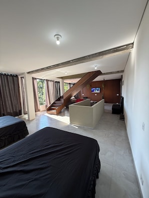 Ein modernes Hotelzimmer mit einem großen Bett, einem Schreibtisch, einem Fernseher und einer Treppe, die zu einer erhöhten Ebene führt.