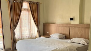 A hotel room with a large bed, a wooden headboard, a bedside table, and a window with curtains. - Cozzy Lekjon 2 Homestay (SAMOSIR)