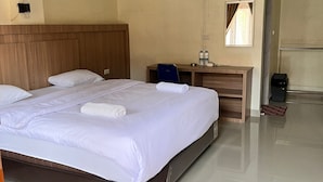 A hotel room with a large bed, a wooden headboard, a desk with a chair, a wall-mounted fan, and a window with curtains. - Cozzy Lekjon 2 Homestay (SAMOSIR)