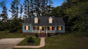 A two-story house with a front porch, a flag, and a well-maintained lawn.