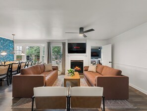 Una sala de estar moderna con sofás, chimenea, televisor y comedor con sillas y mesa.