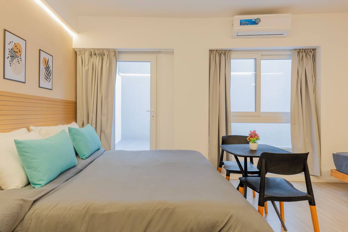 Ein Hotelzimmer mit einem Bett, einem Tisch mit Stühlen, einer Klimaanlage und einem Fenster mit Vorhängen.