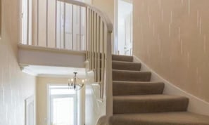 Un escalier avec une rampe incurvée menant à un palier.