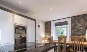 A modern kitchen with built-in appliances, a dining area with wooden furniture, and a stone accent wall.