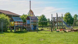Een speeltuin met een glijbaan, klimconstructies en een omheind gebied.