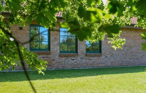 Ein Backsteinhaus mit drei Fenstern und einem grünen Rasen.