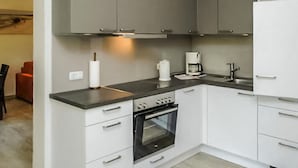 A modern kitchen with grey cabinets, a black countertop, a built-in oven, and a coffee maker. - Beautiful apartment in Ribnitz-Damgarten with house a panoramic view (Ribnitz-Damgarten)