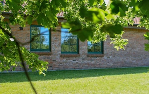 Ein Backsteinhaus mit drei Fenstern und einem grünen Rasen.